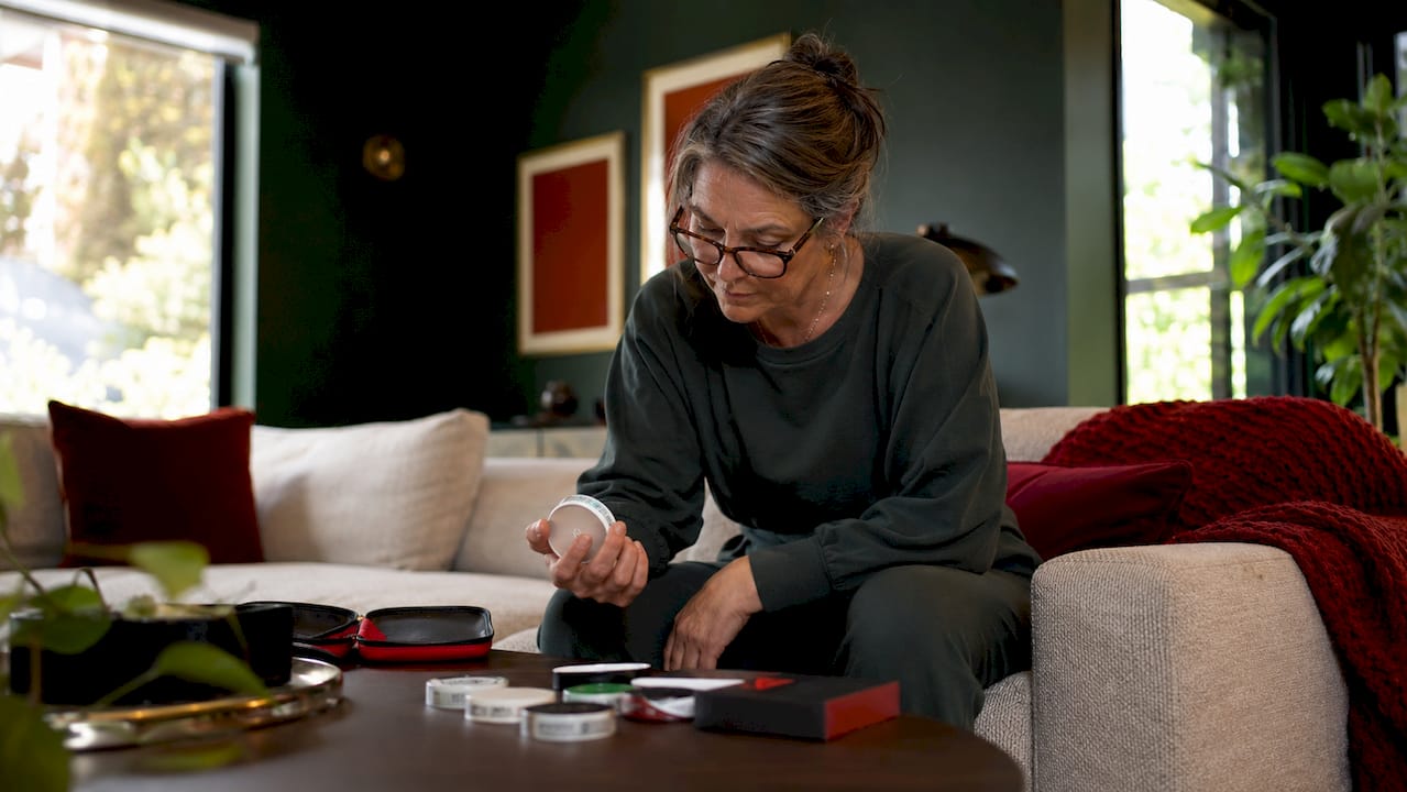 Woman choosing oral nicotine pouch at kitchen table